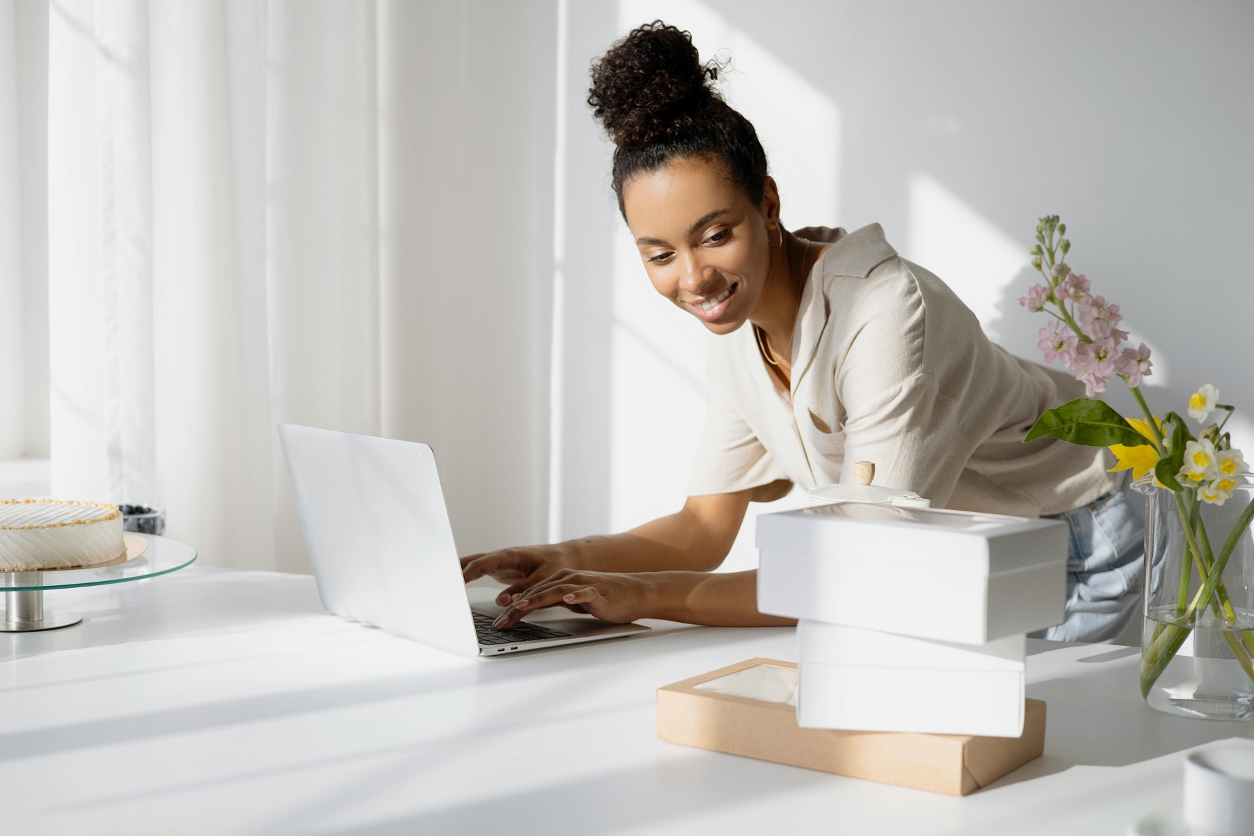 A Black small-business owner working at a laptop in an organised product studio